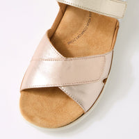 Close-up of a sandal with metallic pink and brown straps on a white background